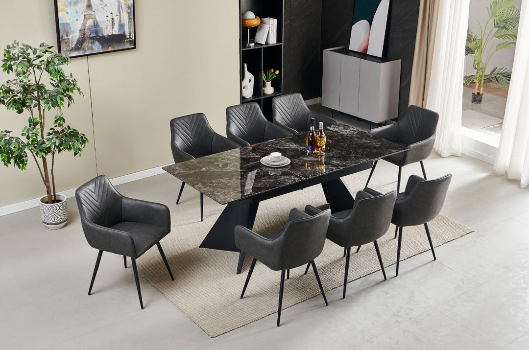 An extendable dining table in black with six dark grey leather chairs, set in a room with minimalist decor.