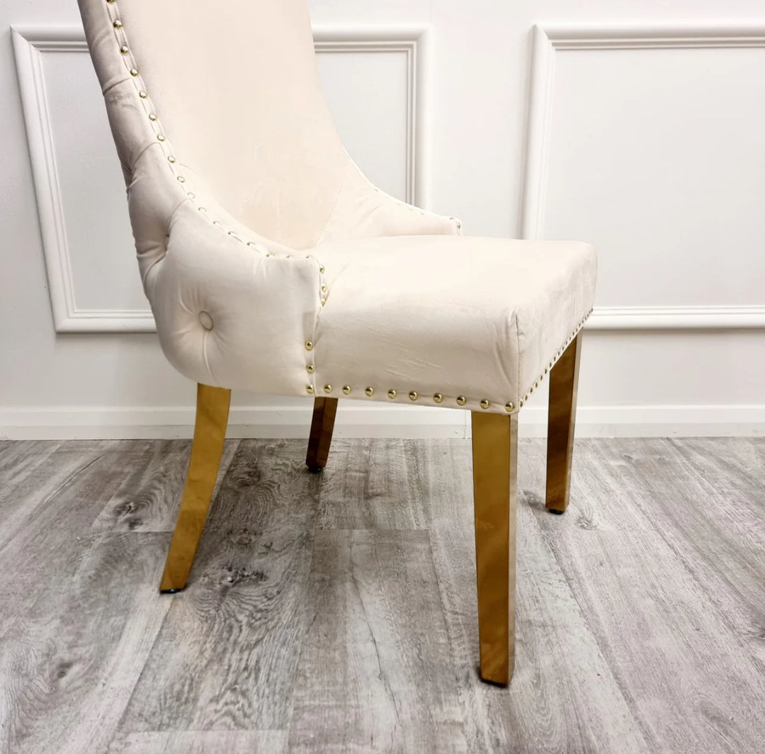 Two Kensington cream dining chairs with gold legs and deep buttoned back design, one showing the side profile and the other showing the back detail.