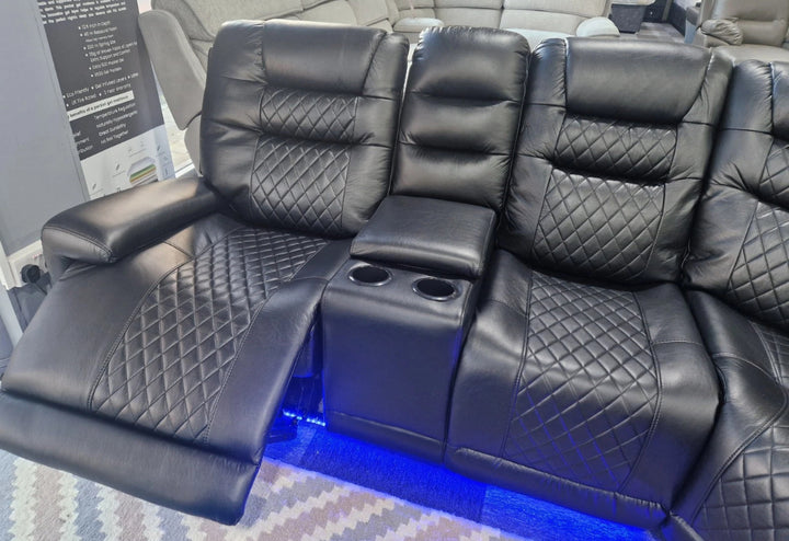 Black leather recliner seats with diamond stitching in a showroom setting.