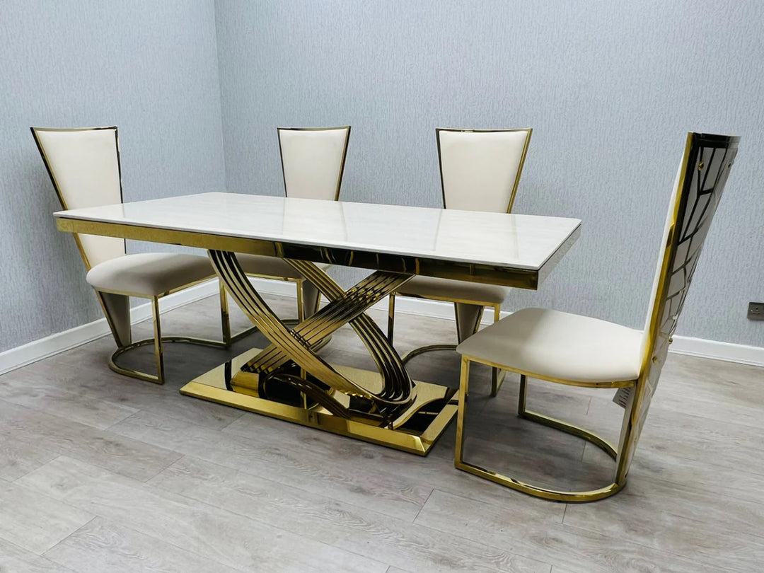 A white marble dining table with gold accents accompanied by chairs with white upholstery and gold frames.