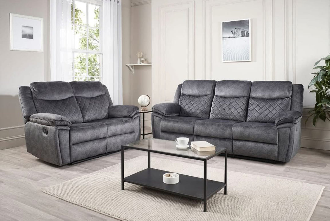 A silver grey leather recliner sofa set consisting of a three-seater sofa, a two-seater sofa, and an armchair, arranged in a living room setting with a center table.