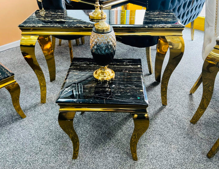A black and gold marble console table with gold-colored legs, displayed in a room setting.
