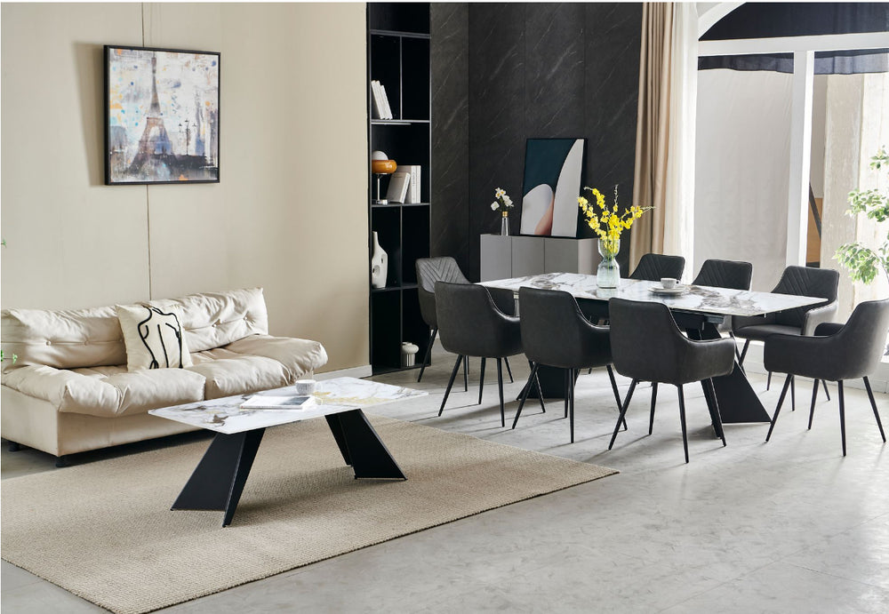 An extendable white dining table with dark grey leather chairs arranged around it, set in a modern living space.