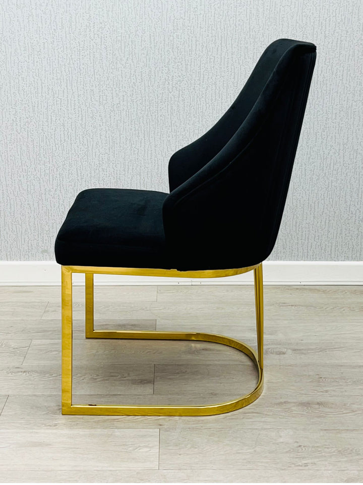 A black chair with a gold frame, positioned against a neutral background.