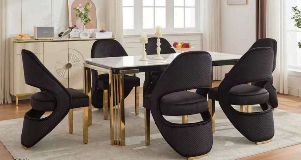 A rectangular white dining table with gold legs, surrounded by black and gold chairs with a contemporary design.