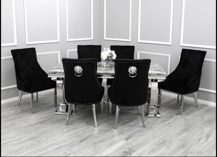 A dining set featuring a light grey marble tabletop with a rectangular shape and black leather chairs with decorative gold-colored knobs.