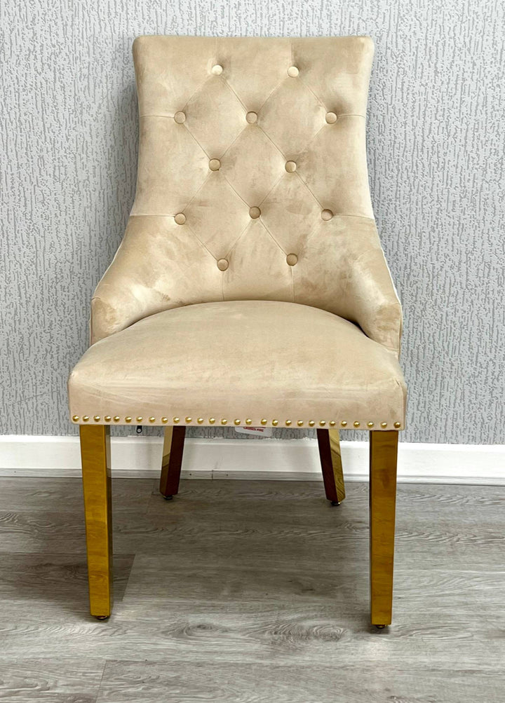 Beige upholstered chair with gold legs against a gray wall.