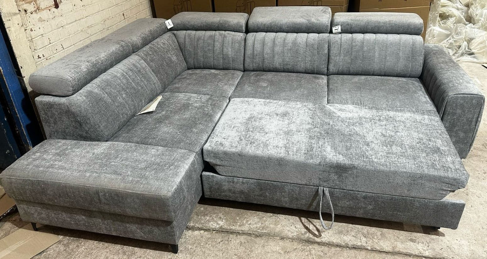 Gray sectional sofa in a store setting with a brick wall background