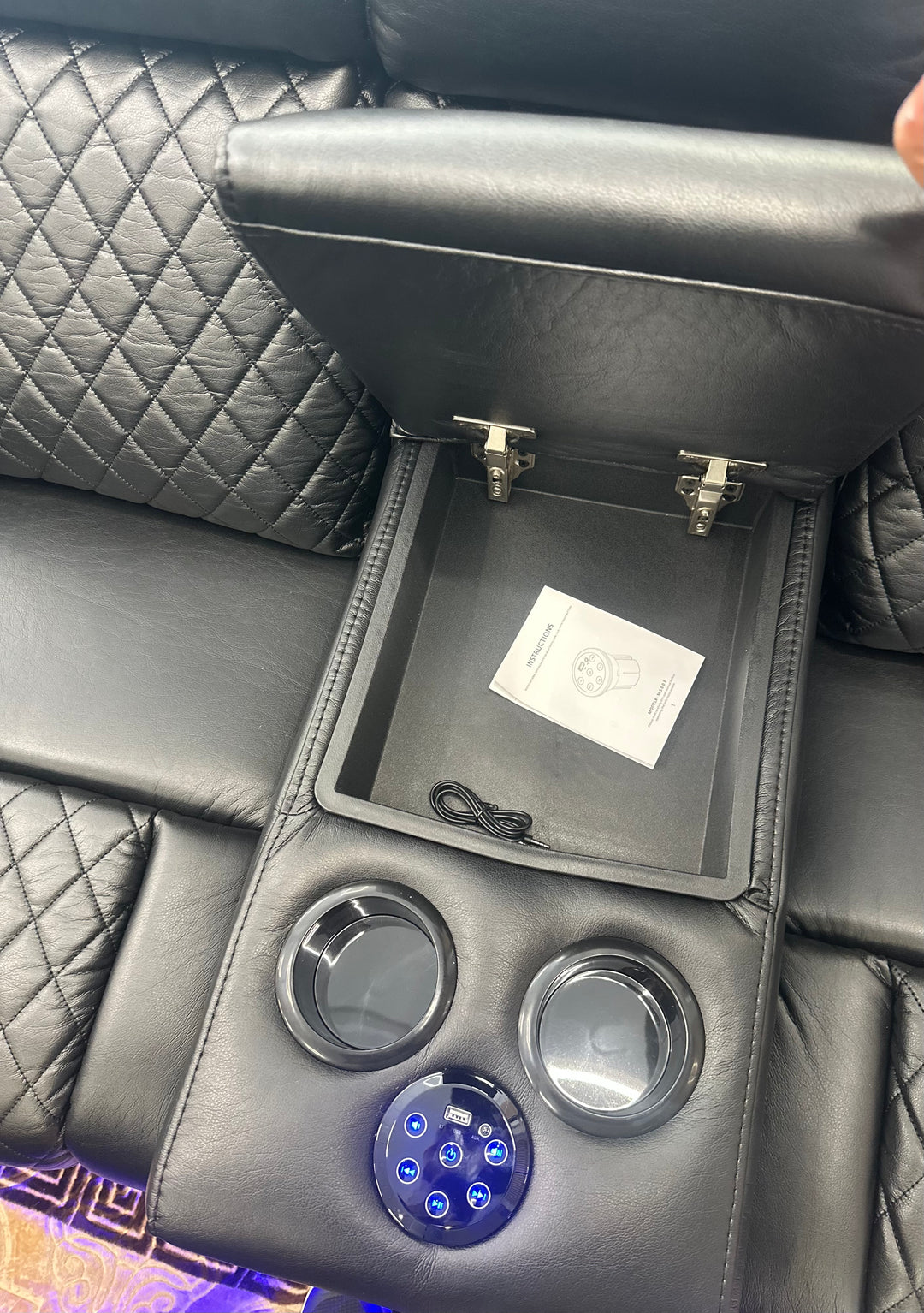 Car console with cup holders and a small screen displaying a logo.