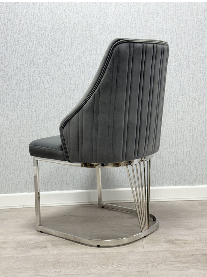 A dark grey leather chair with black metal legs positioned on a rug with a marble wall in the background.