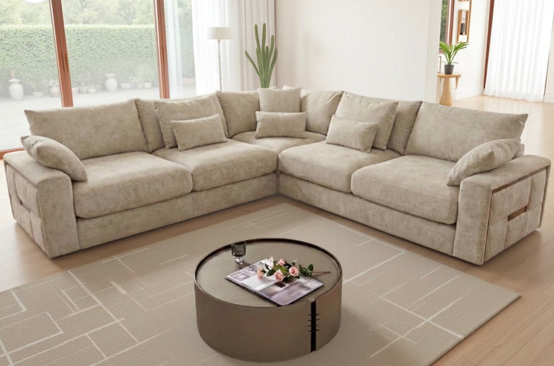 Beige sectional sofa in a living room with a round coffee table and decor items.