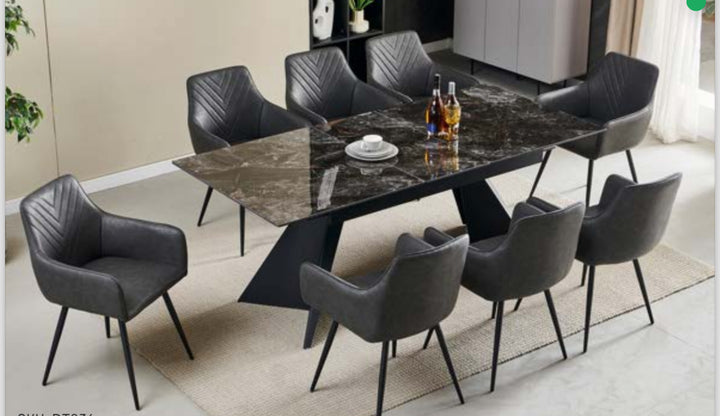 A black extendable dining table with black legs, set in a room with grey chairs around it.