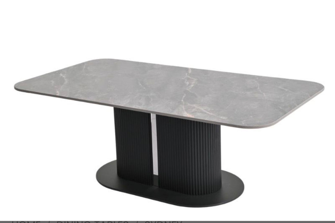 A modern rectangular dining table with a gray marble-patterned top and a black fluted pedestal base on a white background.