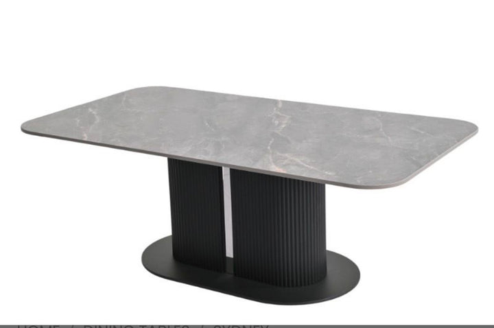 A modern rectangular dining table with a gray marble-patterned top and a black fluted pedestal base on a white background.
