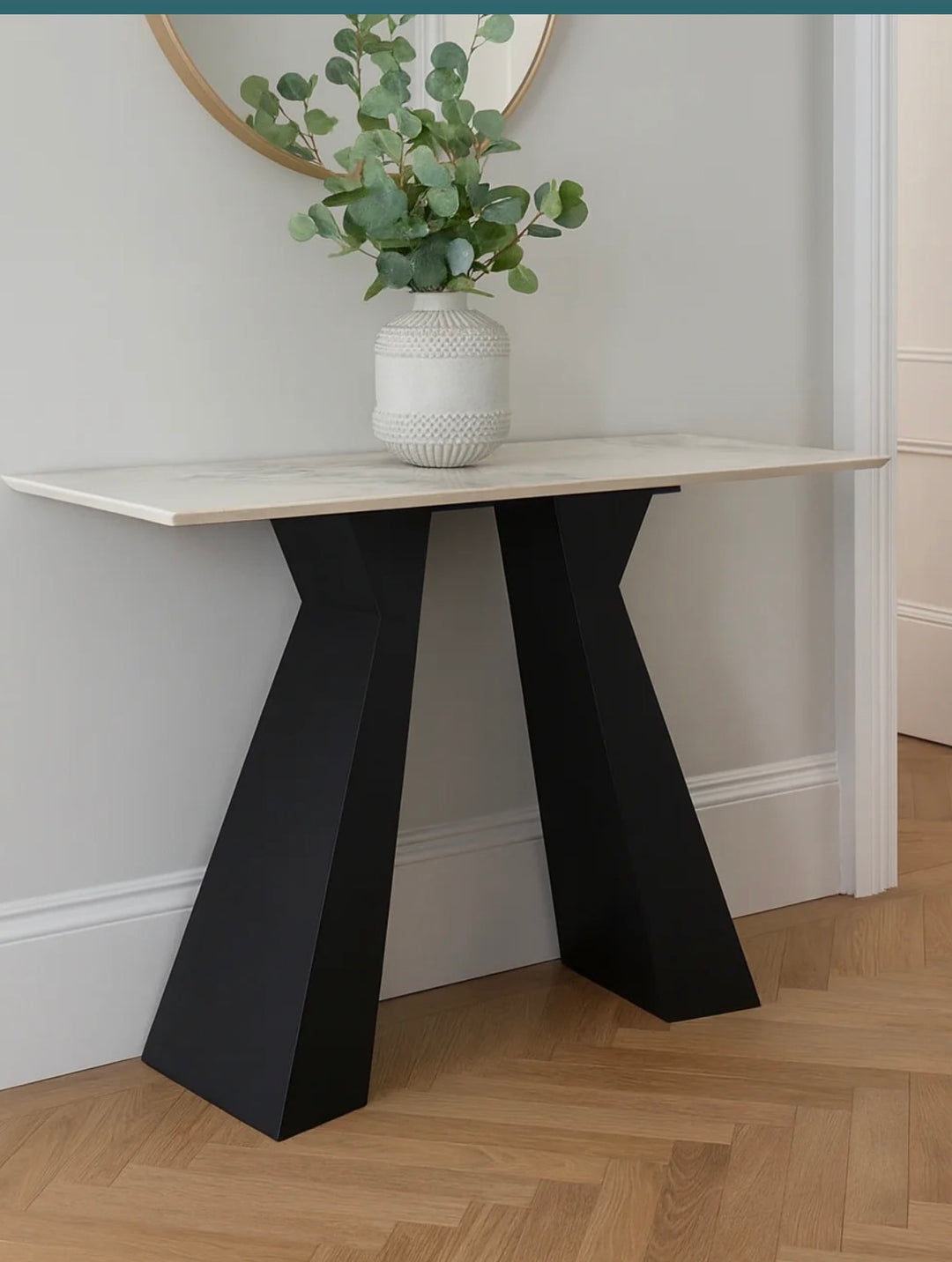 Modern console table with black legs and white top against a neutral wall.