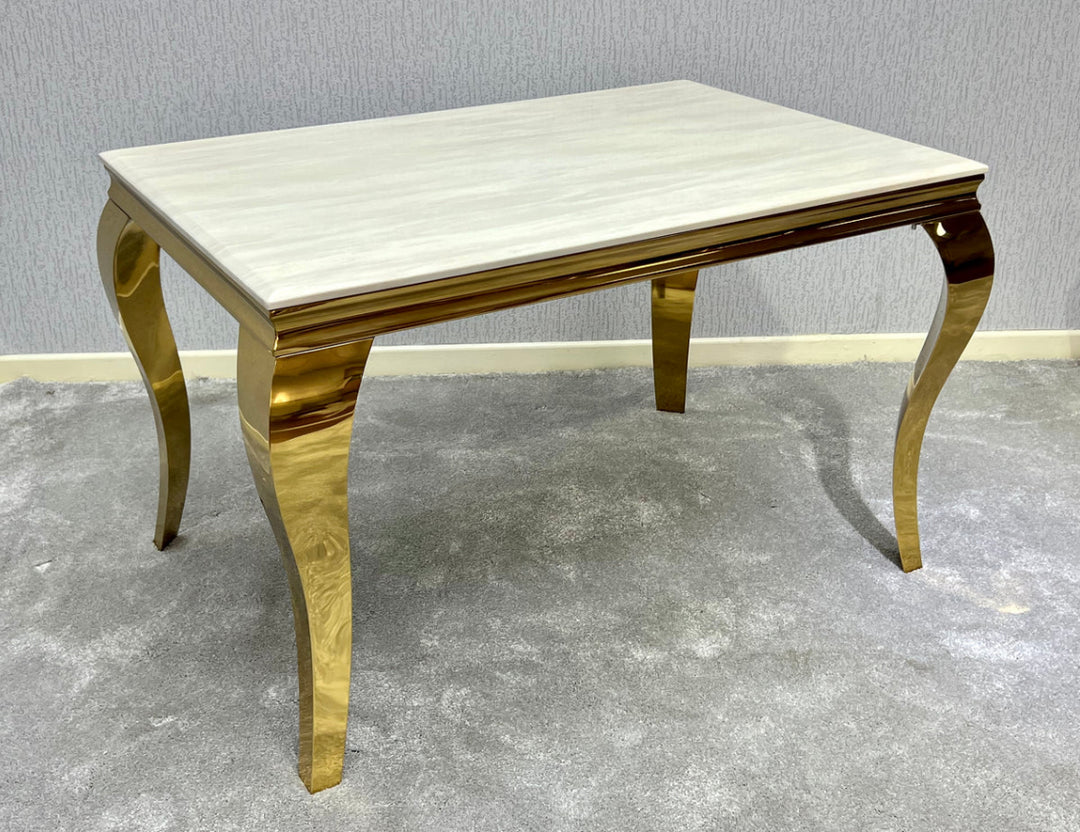 A rectangular cream marble dining table with gold-colored legs and frame.