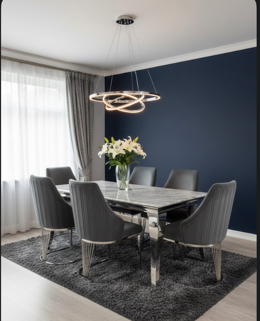 Modern dining room with marble table and gray chairs against a dark blue wall.