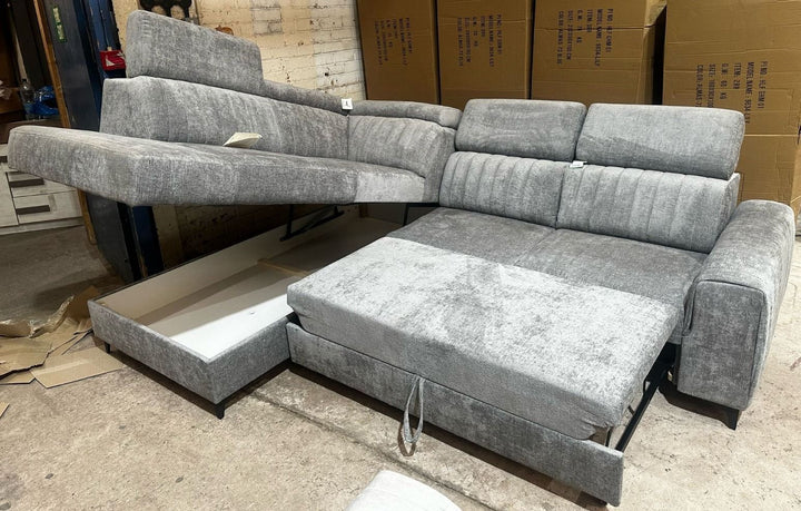Gray sectional sofa with storage drawers in a room with cardboard boxes.