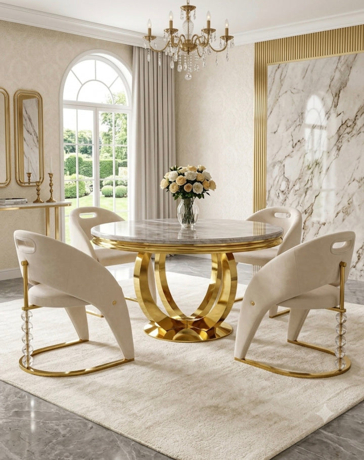 A luxury dining set featuring a round cream marble-top table with a polished gold base, surrounded by four matching cream-colored curved chairs with gold frames, set on a plush cream rug in a high-end dining room.