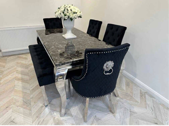 Dining room setup with a black marble table and black chairs with lion emblem on a herringbone floor.