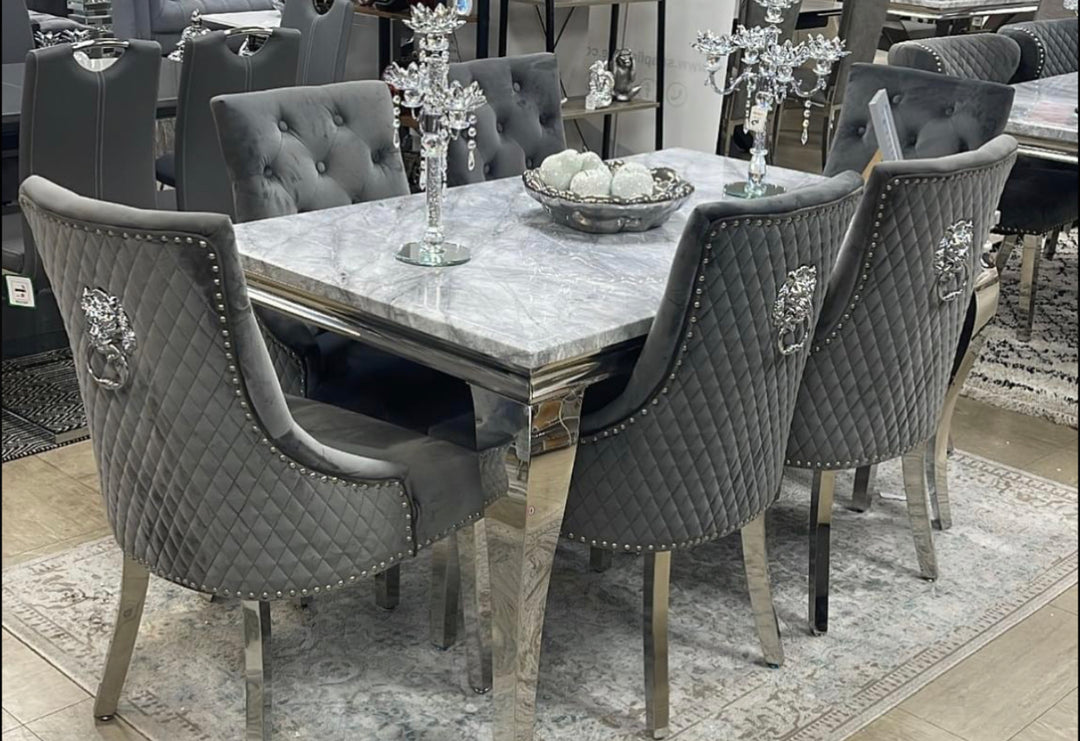 A set of furniture featuring a gray marble dining table with metal legs and six upholstered Grey dining chairs in a room with carpet flooring.
