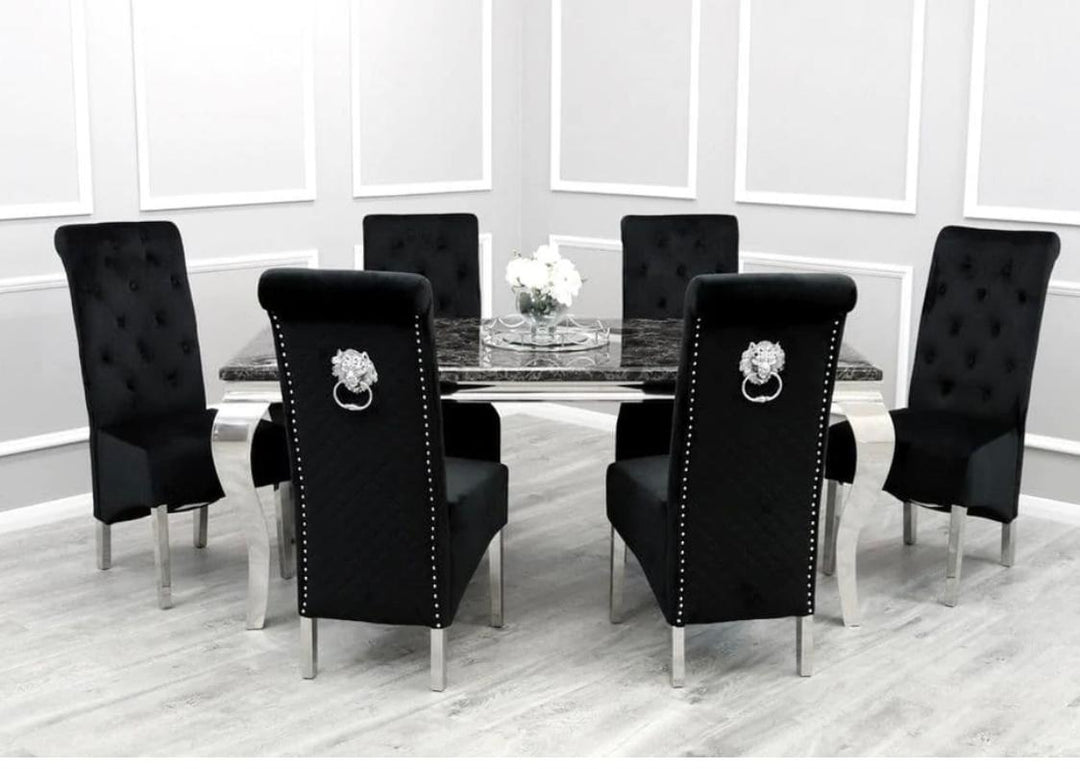 A set of black dining chairs around a black marble dining table with lion knocker designs, placed on a grey floor with white walls in the background.
