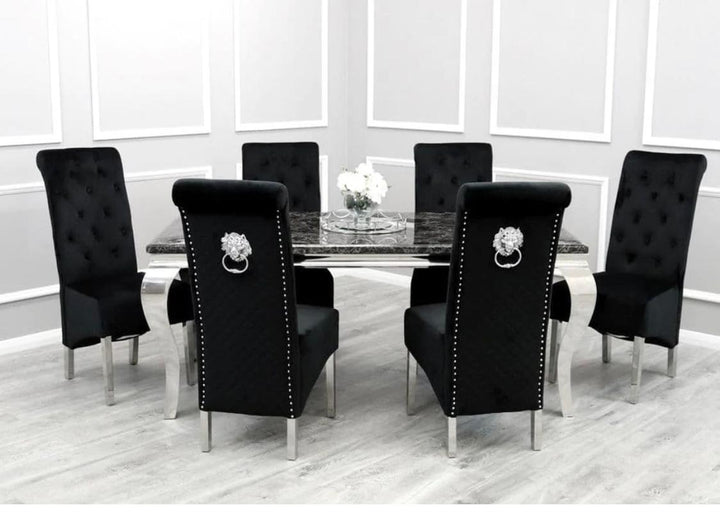 A set of black dining chairs around a black marble dining table with lion knocker designs, placed on a grey floor with white walls in the background.